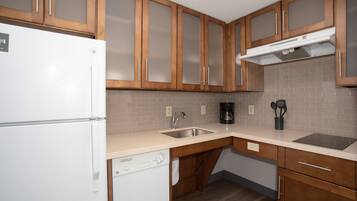 A kitchen with wooden cabinets, a white refrigerator, a dishwasher, a sink, and a coffee maker.