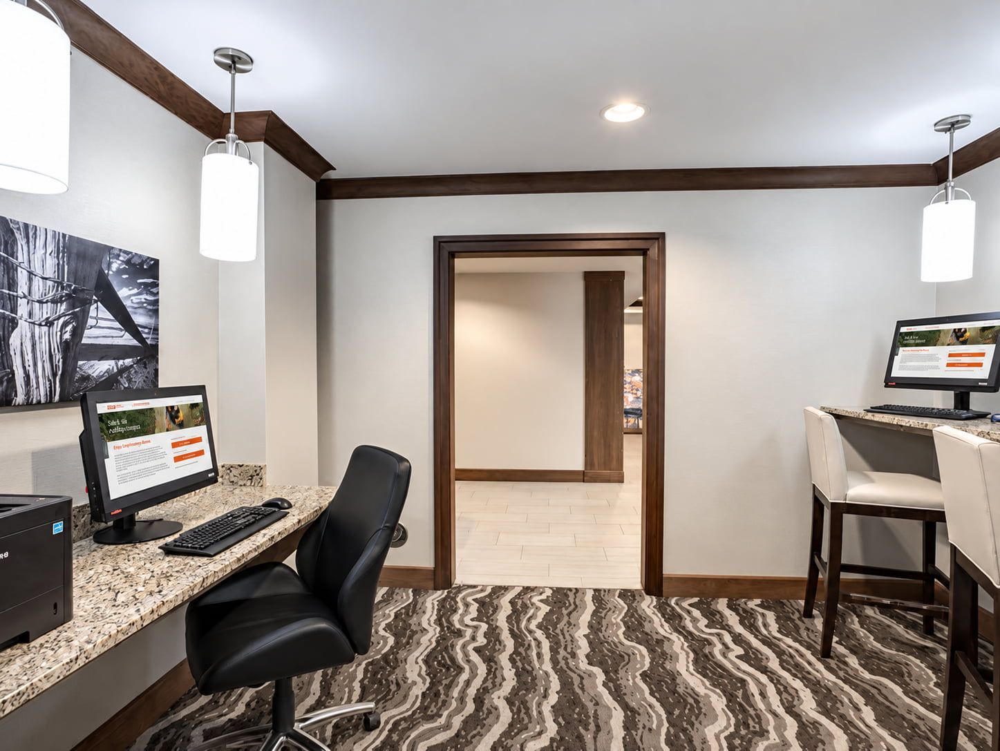 A hotel room with a desk, computer, and chair. There is a door leading to another room.