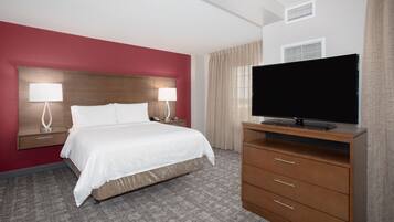 A hotel room with a bed, two bedside lamps, a TV on a wooden stand, and a carpeted floor.