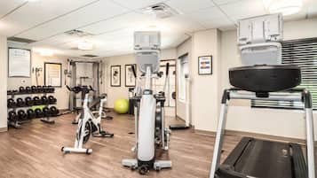 A gym with cardio machines, dumbbells, and a treadmill.