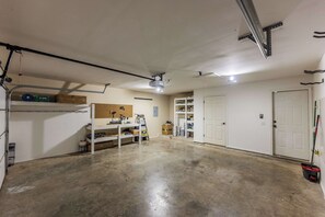 A garage with a workbench, shelves, a pegboard, and a door. - The Landing | Bike to Downtown + Coler (Bentonville)