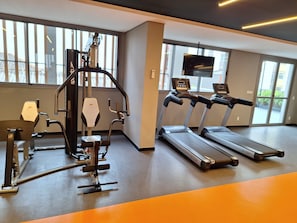 A gym with exercise equipment, a treadmill, and a television screen. - Modern studio apartment 200m from Paulista Avenue with a closed bedroom. (SÃO PAULO)
