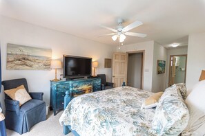 Ein Schlafzimmer mit einem Bett, einem Fernseher, einem Schminktisch und einem Deckenventilator.