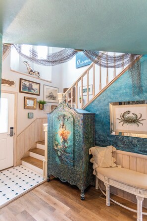 Eine Treppe mit Holzbalkon, einer Sitzbank und einer Wand mit gerahmten Kunstwerken.