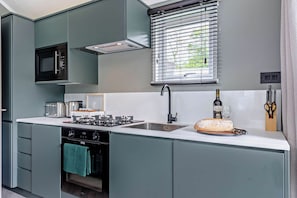 A modern kitchen with a built-in microwave, a gas stove, and a sink. - Prion 1.0 Pet (Denbigh)