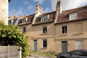 A row of terraced houses with pitched roofs, a wooden fence, and a car parked in front. - 3-Bed Home in Batheaston, Sleeps 6 (Batheaston)