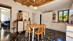 Une cuisine équipée d’une table et de chaises, de meubles en bois et d’une fenêtre donnant sur un paysage verdoyant.
