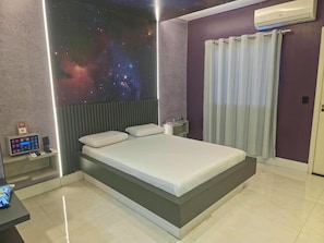 A modern bedroom with a bed, a nightstand, a wall-mounted air conditioner, and a control panel. - Luxus Motel (Tucano)