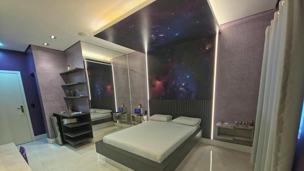Ein modernes Schlafzimmer mit einem großen Bett, integrierten Regalen, einer Wand mit Galaxie-Motiv und einem minimalistischen Design.