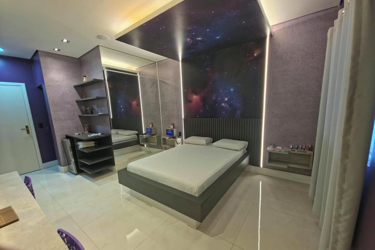 A modern bedroom with a large bed, built-in shelving, a galaxy-themed wall, and a minimalist design.