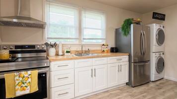 A modern kitchen with a stainless steel range, a built-in oven, a double sink, and a refrigerator.