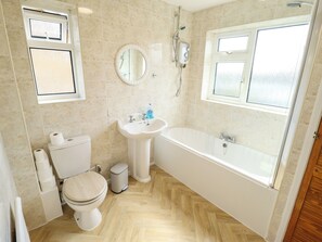 A bathroom with a toilet, sink, and bathtub. - Mariner's Nook (Cleethorpes)