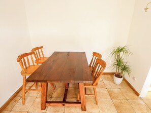 A rectangular wooden dining table with four chairs, a potted plant, and a tiled floor. - Mariner's Nook (Cleethorpes)