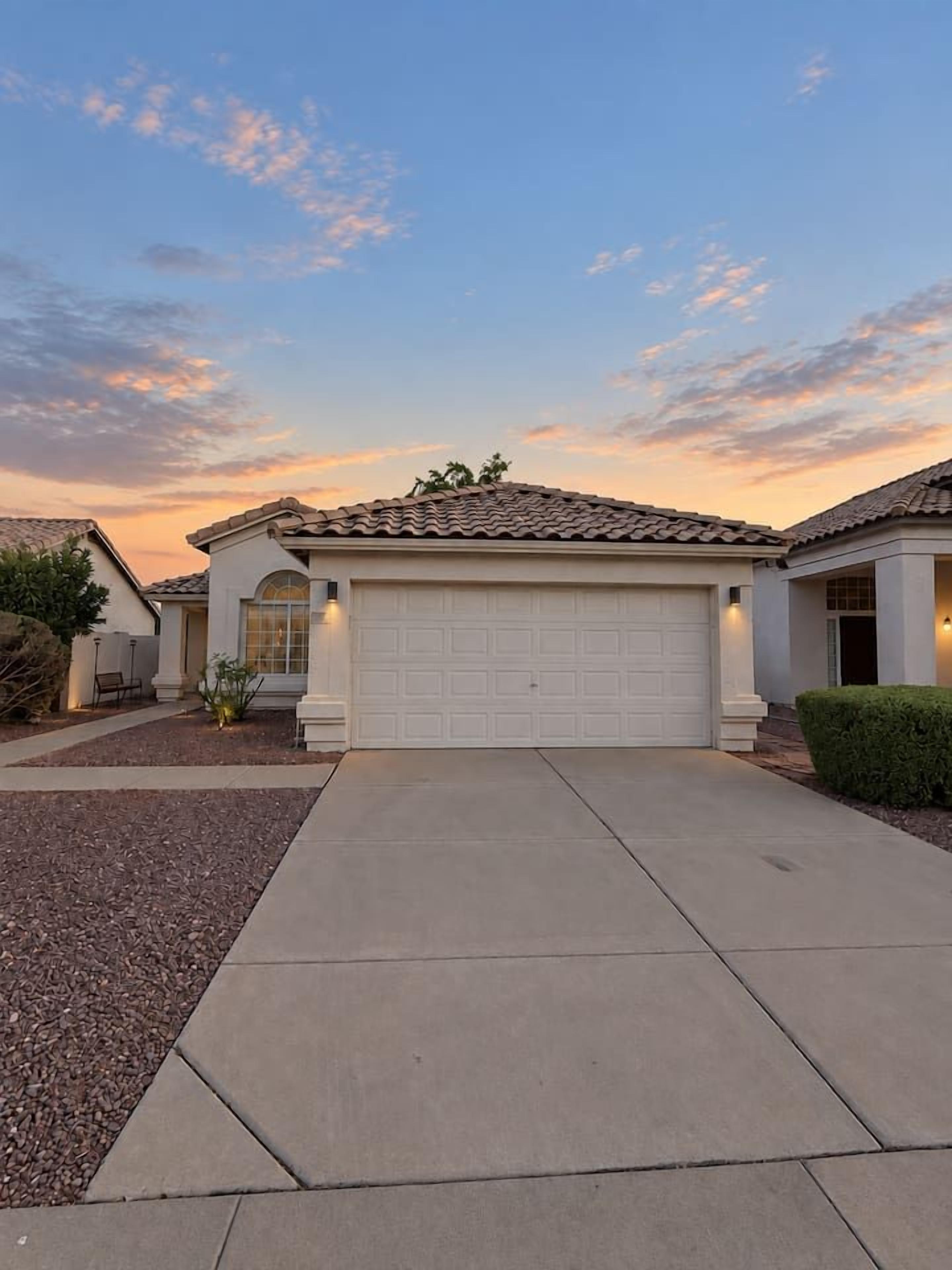 A residential house with a garage, driveway, and a well-maintained lawn.