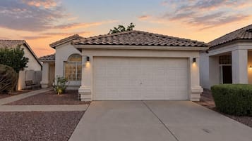 A residential house with a garage, driveway, and a well-maintained lawn.
