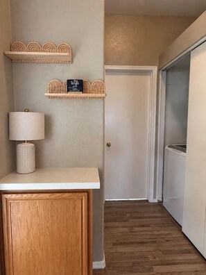 A hallway with a wooden cabinet, a lamp, and two shelves with a 'Wifi' sign.
