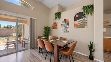 A dining area with a table set for six, surrounded by chairs, and a sliding glass door leading to an outdoor patio.