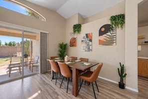 A dining area with a table set for six, surrounded by chairs, and a sliding glass door leading to an outdoor patio. - Pool, Tub & Mini Golf |SF Stadium, Westgate, more (Glendale)