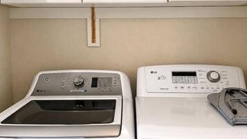 A laundry area with two white washing machines and cabinets above.