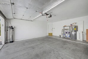 A spacious, unfinished interior with a concrete floor, a water heater, and a ceiling with exposed ductwork.