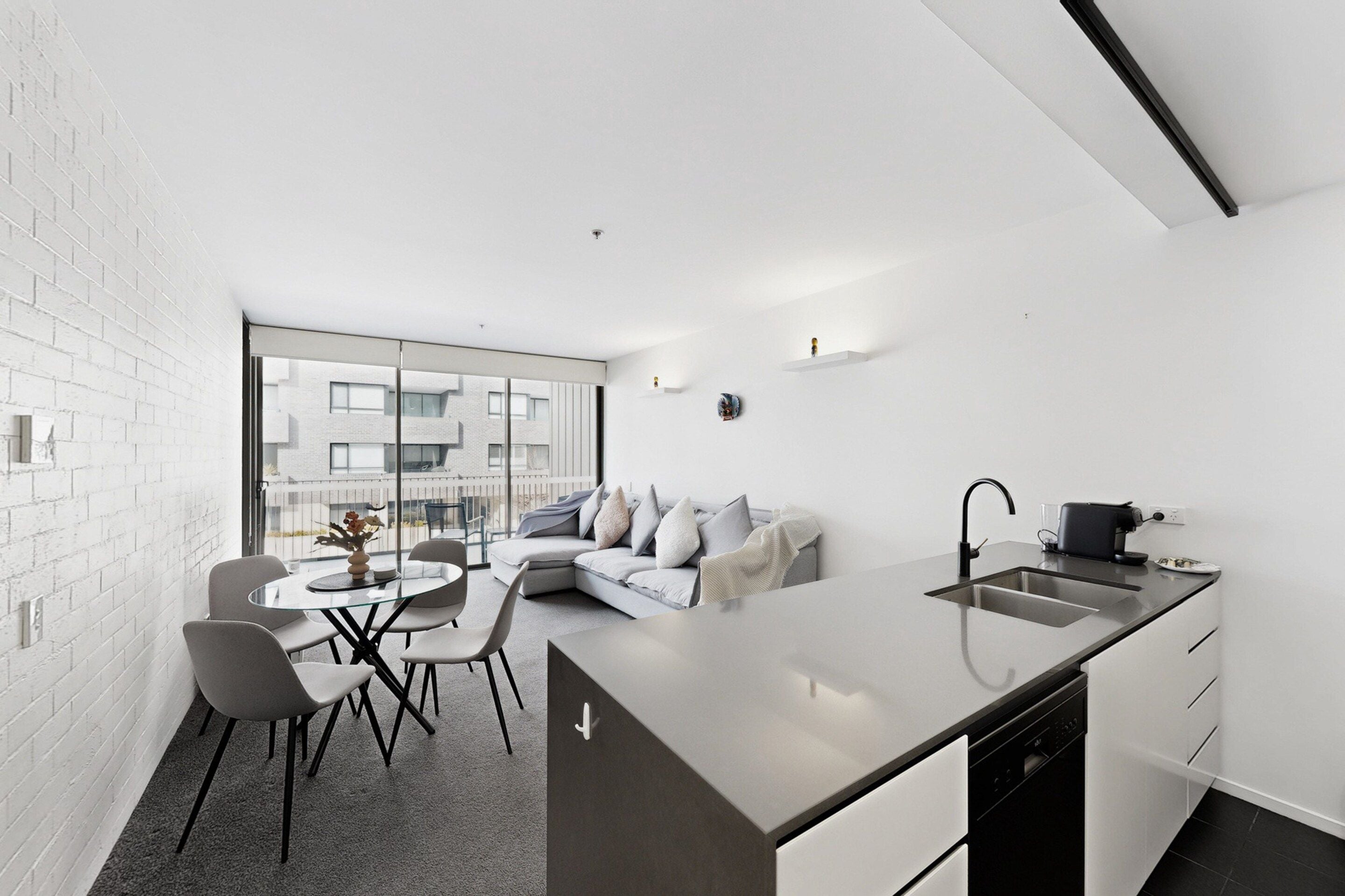 A modern kitchen with a large island, a dining area with a round table and chairs, and a sofa in the living area.
