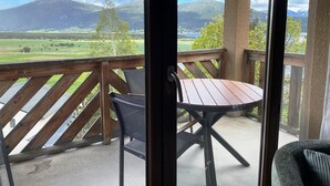 Een balkon met een tafel en stoelen, met uitzicht op een bergachtig landschap.
