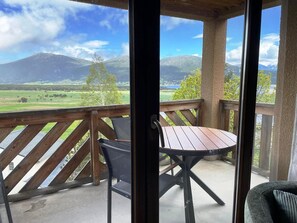 Ein Balkon mit Tisch und Stühlen mit Blick auf eine gebirgige Landschaft.