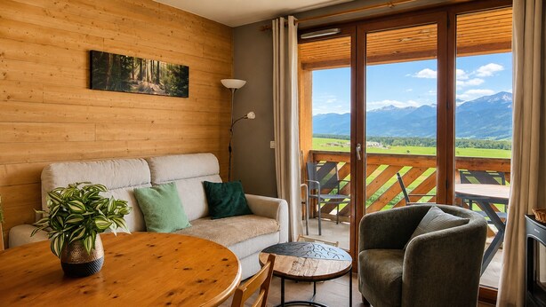 Een gezellige kamer met een houten wand, een bank, een tafel en uitzicht op bergen.