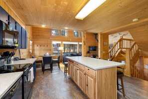 A wooden cabin interior with a kitchen, dining area, and a staircase. - Cabin w/ Hot Tub & Fireplace, Near Peak 7 Trails (Breckenridge)