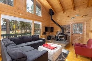 A cozy cabin interior with a sofa, a red chair, a fireplace, and a stone wall. - Cabin w/ Hot Tub & Fireplace, Near Peak 7 Trails (Breckenridge)
