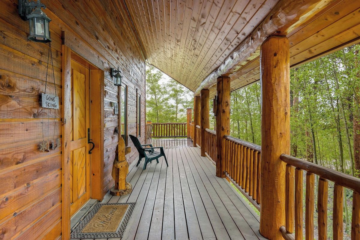 Una cabaña de madera con un porche cubierto, un banco y un cartel que indica 'Gone Skiing'.