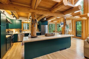 A spacious kitchen with wooden beams, a central island, and a view of the outdoors. - Peak 7 Cabin w/ Ten Mile Range Views, Fireplace (Breckenridge)