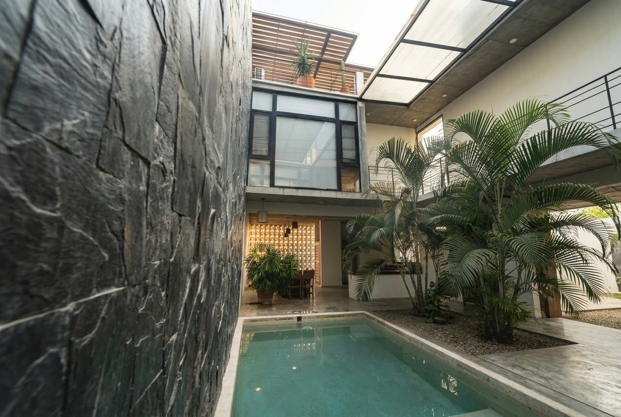 A modern building with a pool, stone walls, and potted plants.
