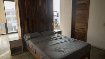 Ein modernes Schlafzimmer mit Bett, Holzwandverkleidung, einem Nachttisch und Blick ins Freie.