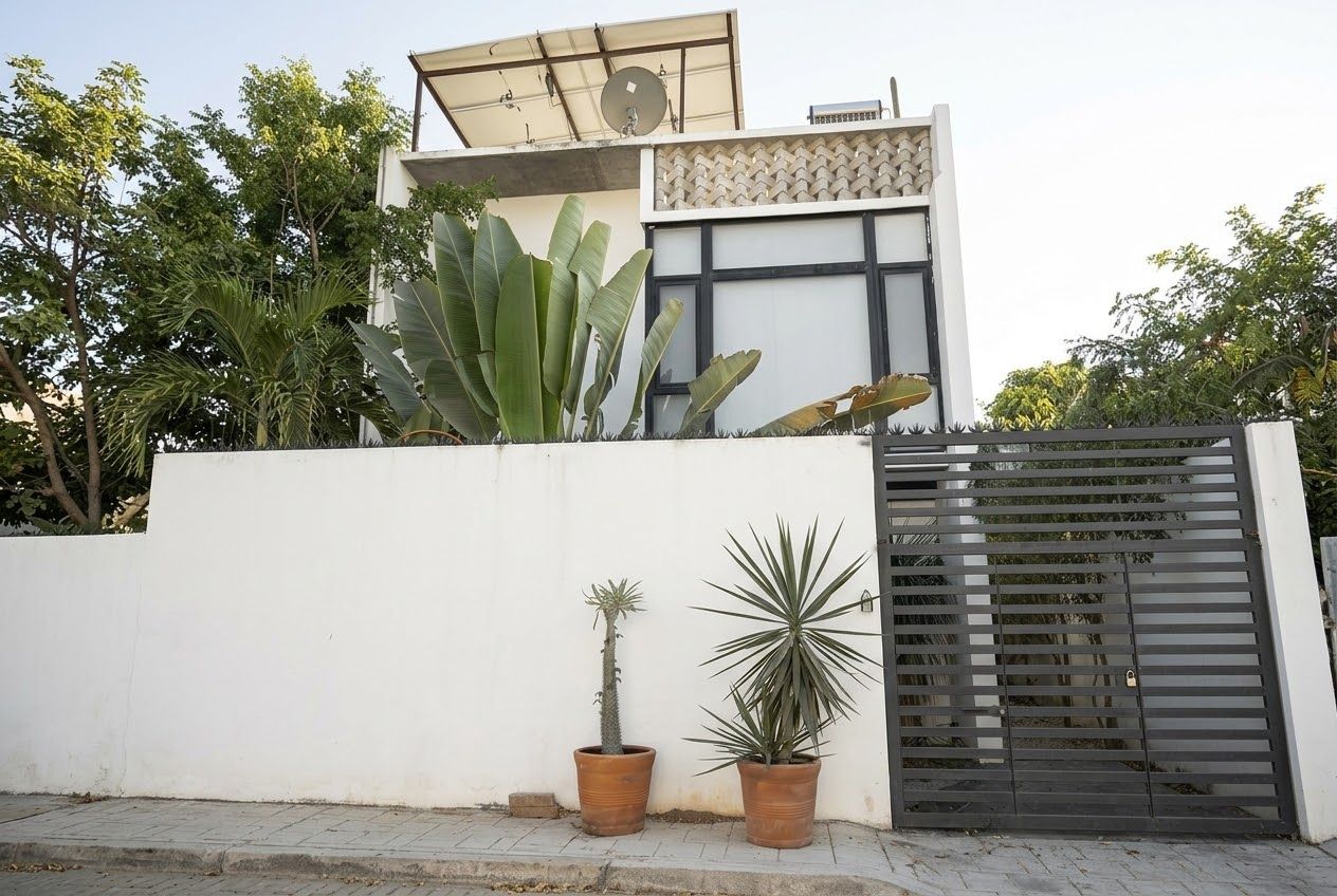 A modern building with a white facade, a satellite dish, and a gated entrance.