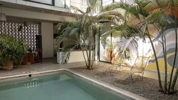 An indoor pool area with palm trees, a seating area, and a modern architectural design.