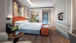 Una camera d'albergo con un letto, un comodino, una lampada e un televisore appeso al muro.