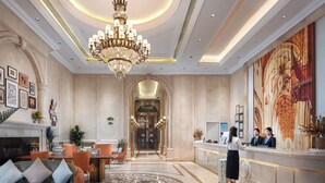 Un'ampia hall d'albergo con un maestoso lampadario, una reception e un grande murale sulla parete.