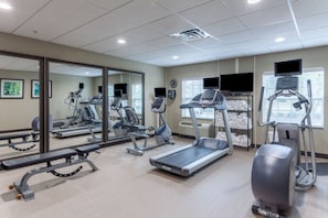 A gym with treadmills, elliptical machines, and weight benches.