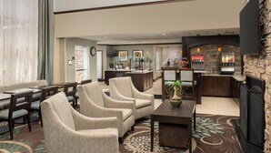 Un hall d’hôtel avec des sièges, un bar à café, une cheminée et un distributeur automatique de Coca-Cola.
