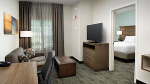 Une chambre d’hôtel équipée d’un canapé, d’un bureau, d’une télévision, d’une petite armoire et d’un lit.