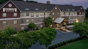 Un hôtel Staybridge Suites avec une façade en briques, de nombreuses fenêtres et une pelouse bien entretenue.