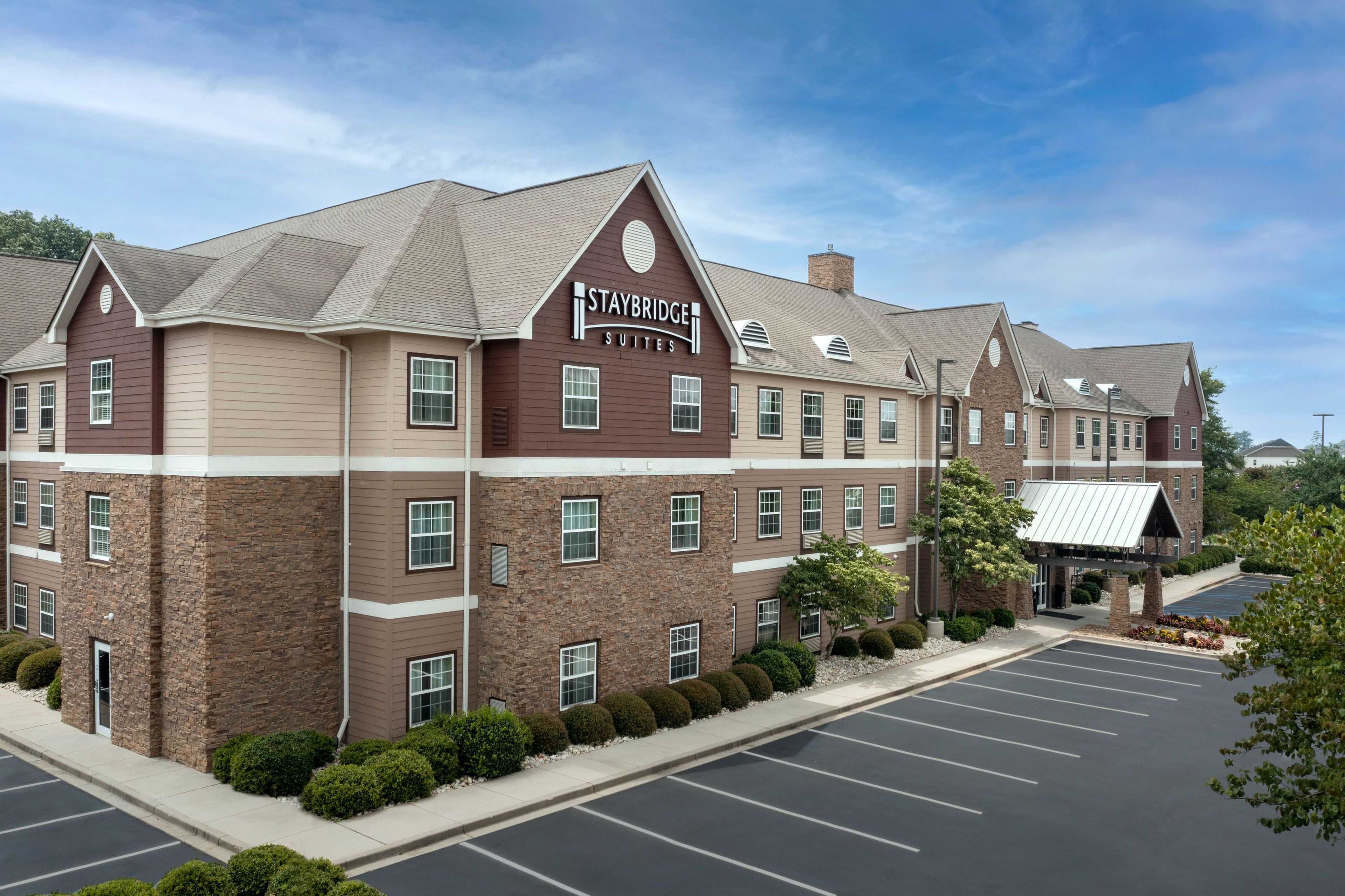 A Staybridge Suites hotel with a brick facade, multiple windows, and a parking lot.