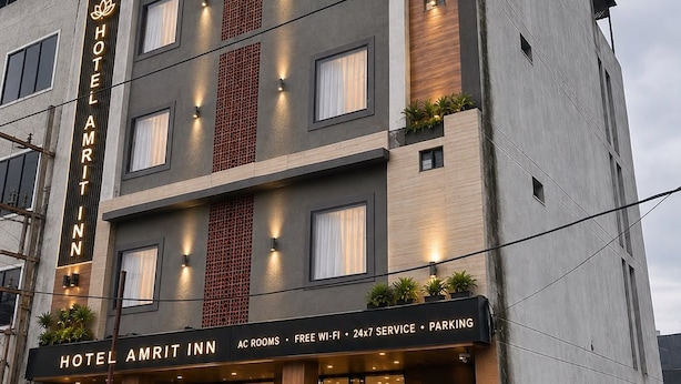Een meerhoog hotelgebouw met een bord waarop 'HOTEL AMRIT PALACE' staat.