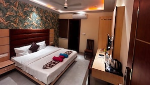 Een hotelkamer met een bed, een bureau, een stoel, een airconditioner en een televisie.