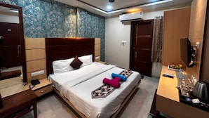 Een hotelkamer met een bed, nachtkastje, kledingkast, airconditioning en een televisie.