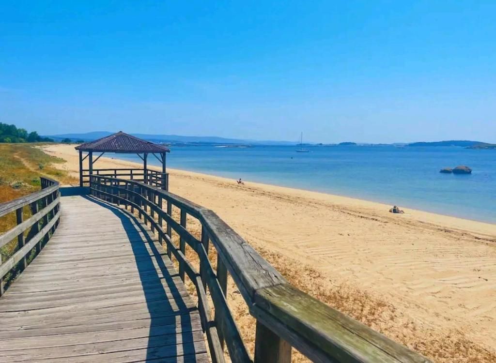 A wooden boardwalk leading to a beach with a gazebo.