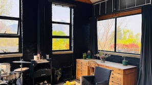A room with a drum set, a radiator, a wooden desk, and a chair.