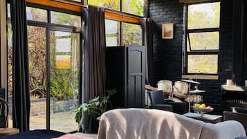 A bedroom with a large bed, a desk, and a chair. There is a chandelier hanging from the ceiling.