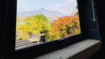 Una ventana con vistas a un paisaje, que incluye árboles y una cadena montañosa.